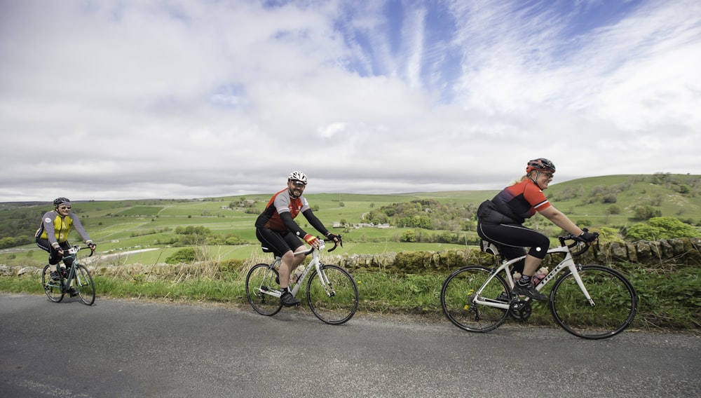 three bicyclists riding down a country road