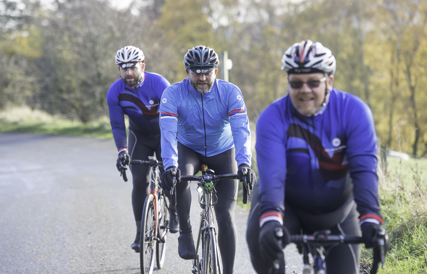 A group of road cyclists in their 40s to 60s riding together