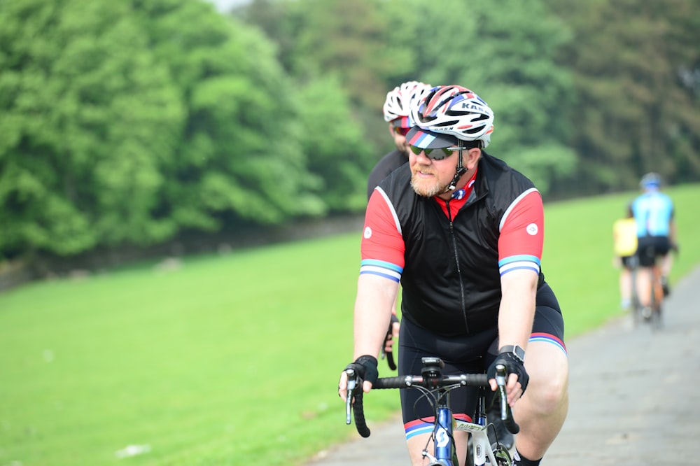 a man riding a bike down a road next to a lush green field