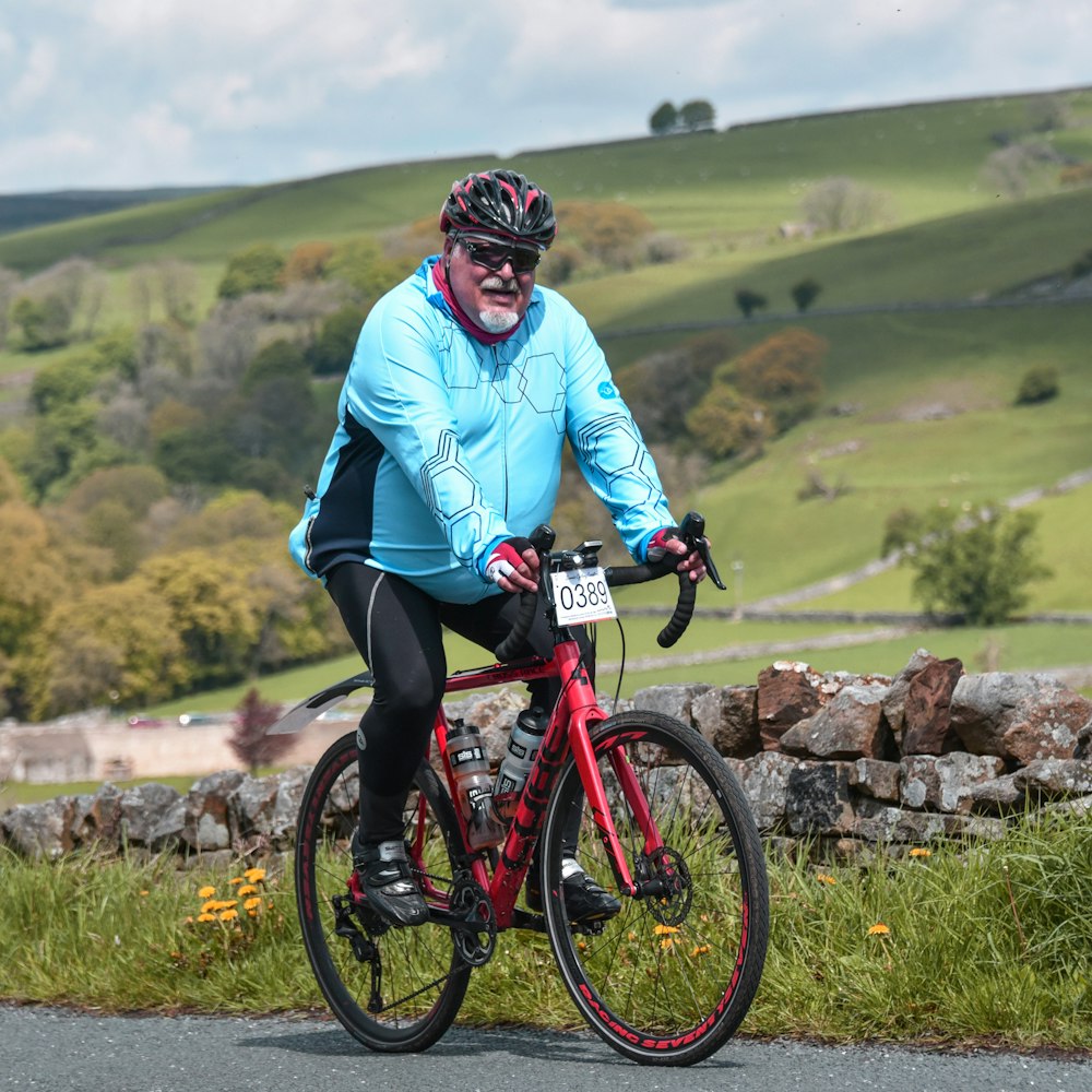 a man riding a red bike down a road