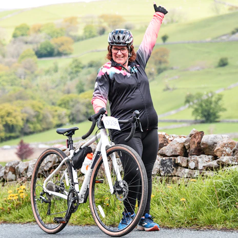 A cyclist crossing the finish line with arms raised in victory during a race.