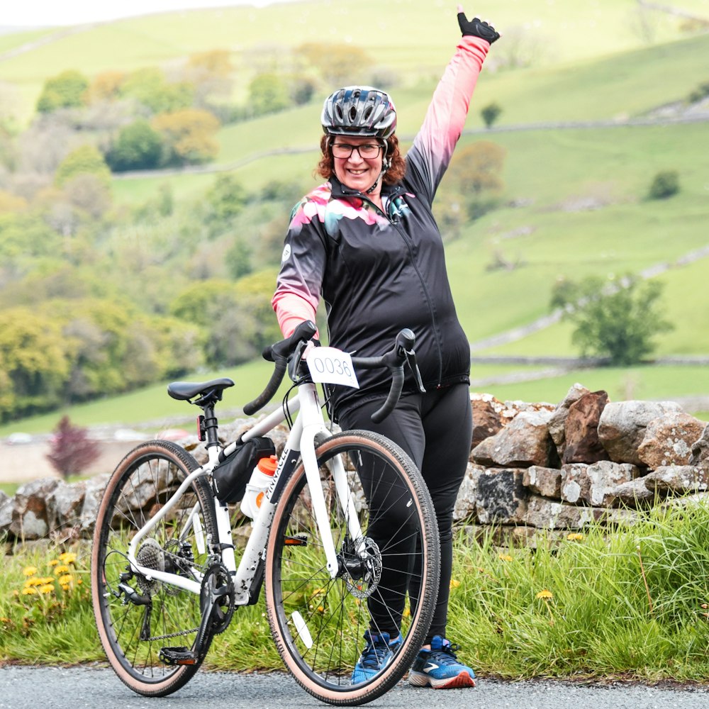 a woman in a black top is holding her bike