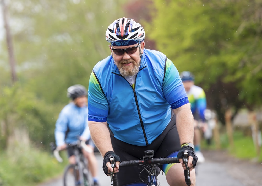 a man riding a bike down a road next to a forest