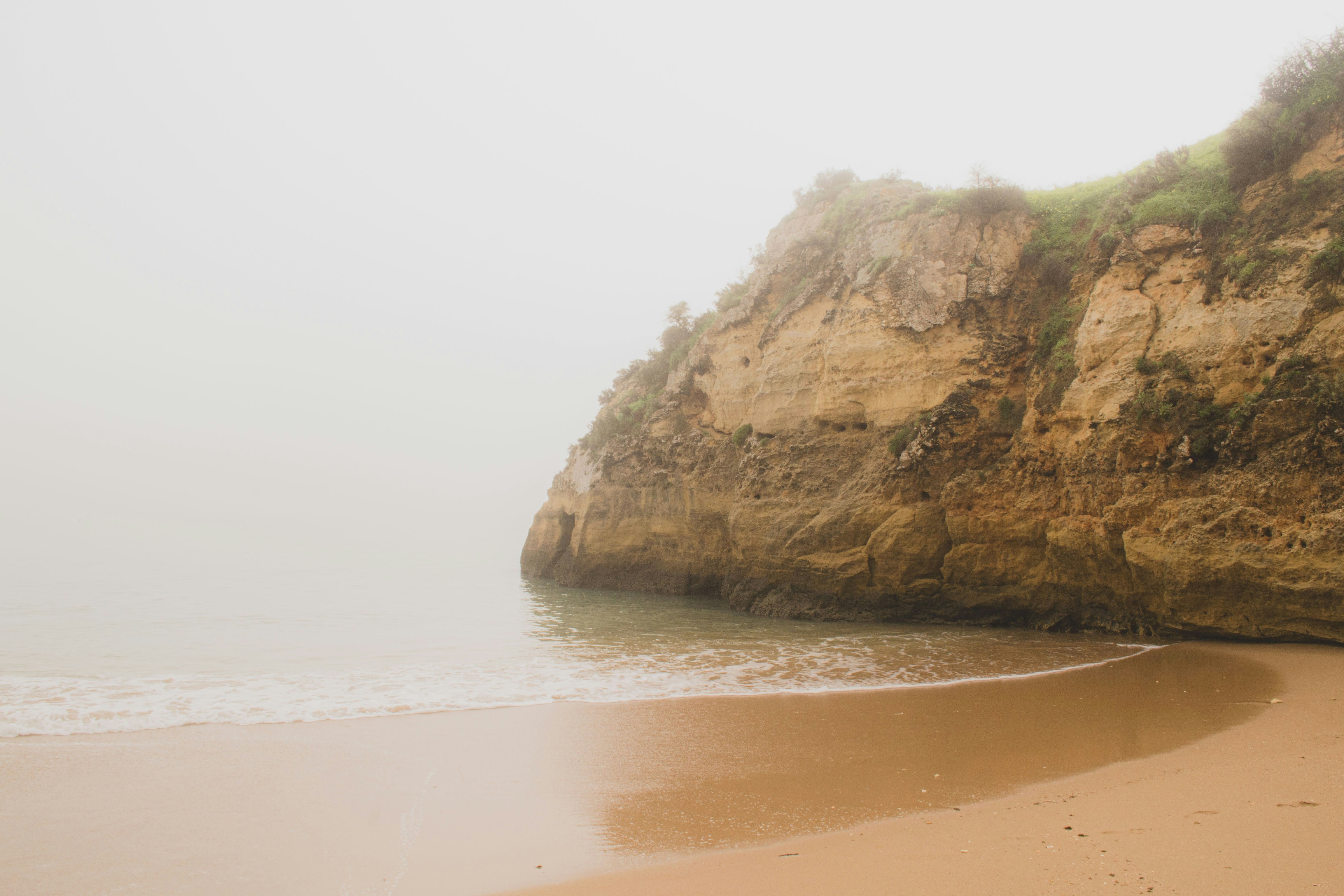 a sandy beach with a cliff in the background