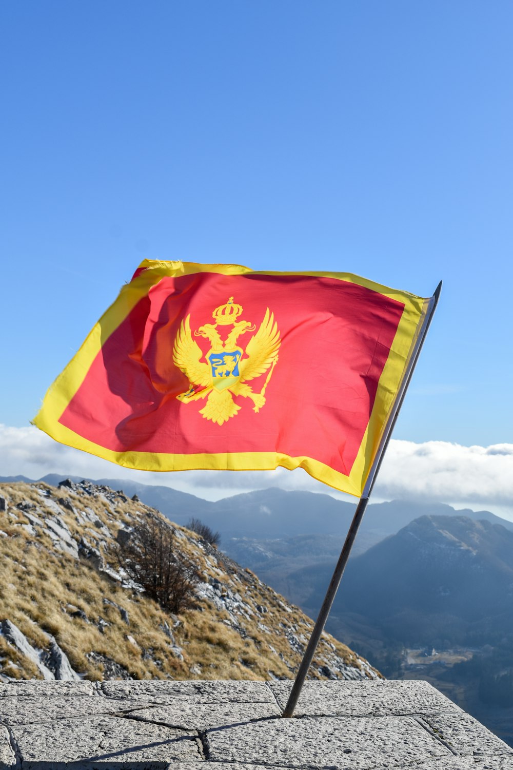 Un drapeau au sommet d’une montagne avec des montagnes en arrière-plan