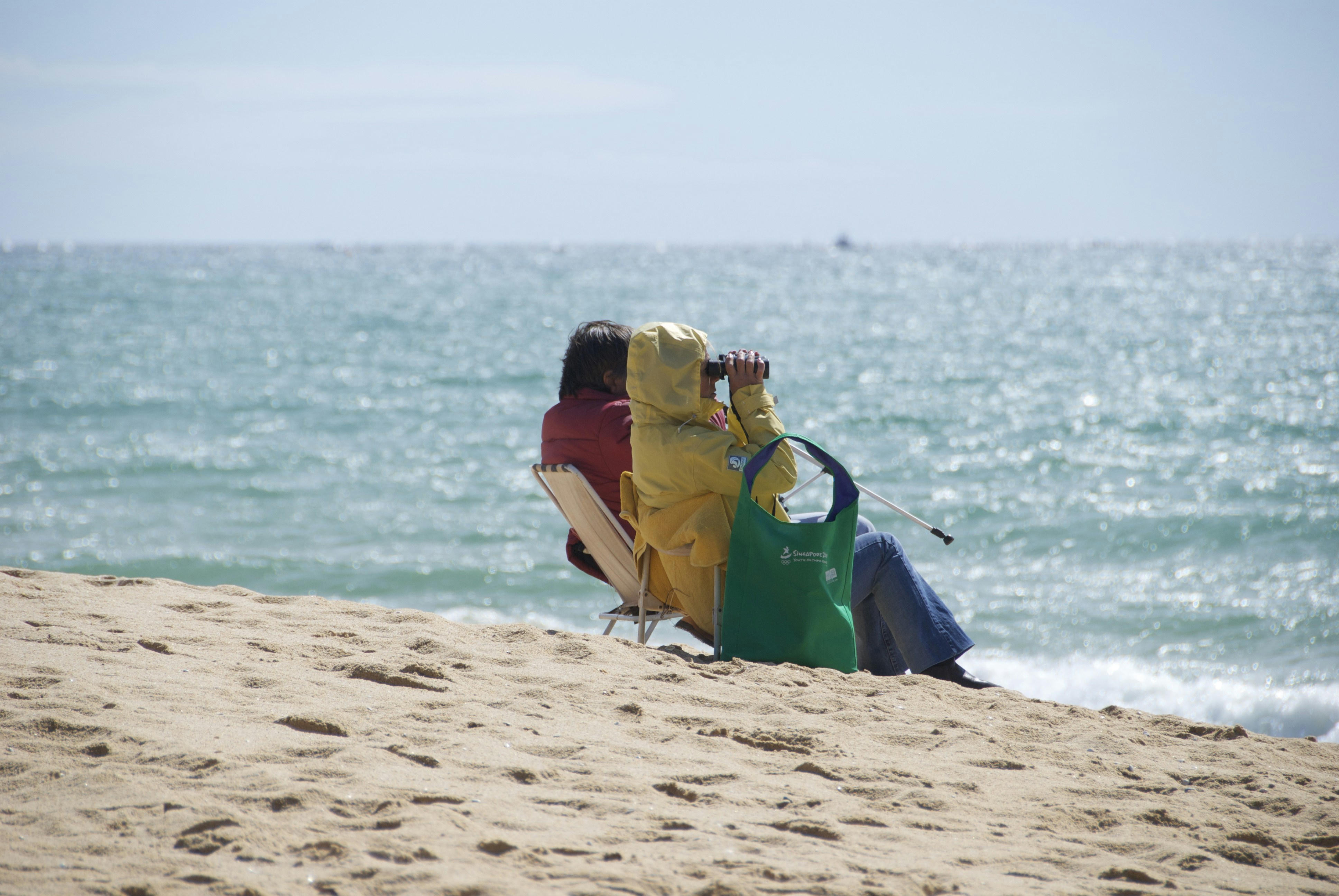 a couple of people sitting on top of a sandy beach
