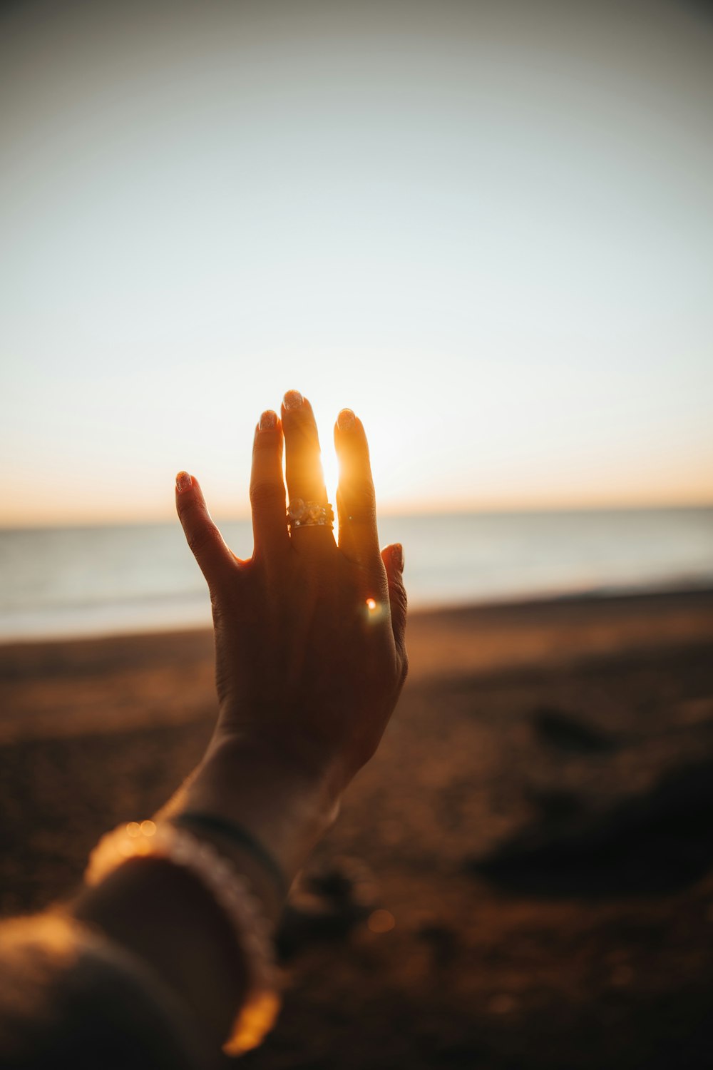 a person holding their hand up to the sun