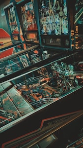 A collection of vintage pinball machines with colorful graphics, including a prominent Star Wars themed game. The machines display intricate designs with various colors and lights, and there is a nostalgic ambiance due to the retro aesthetic.