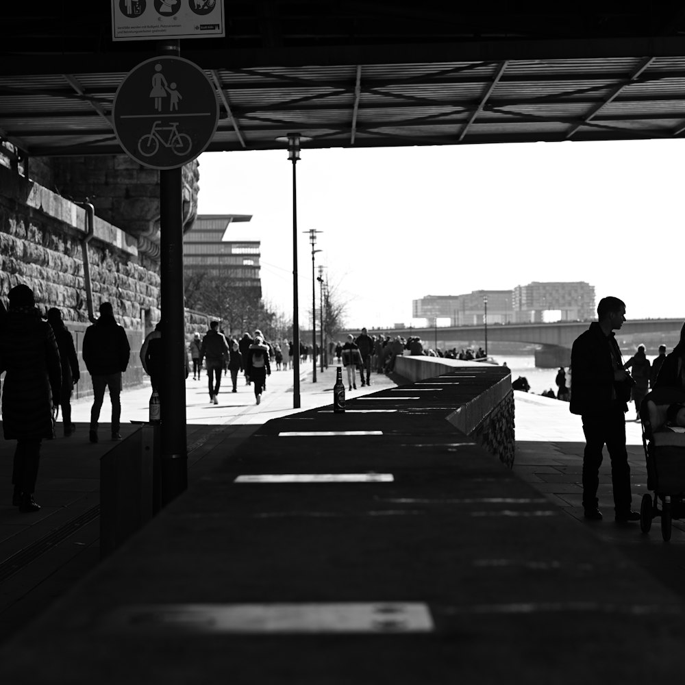 a black and white photo of people walking on a sidewalk