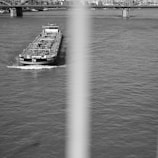 Wide shot of a cargo ship passing under a municipal bridge on an inland waterway.