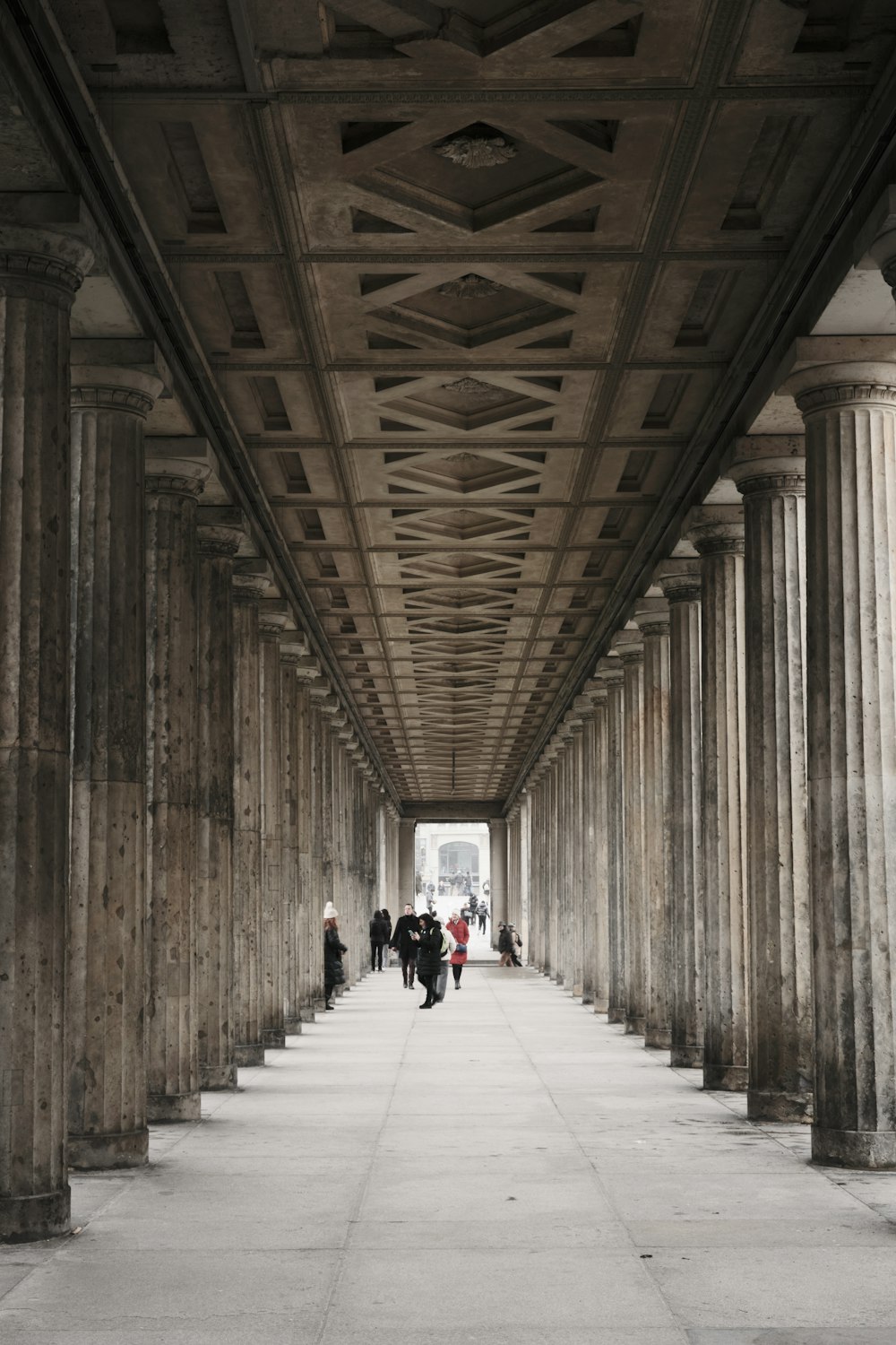 a walkway with columns and people walking down it