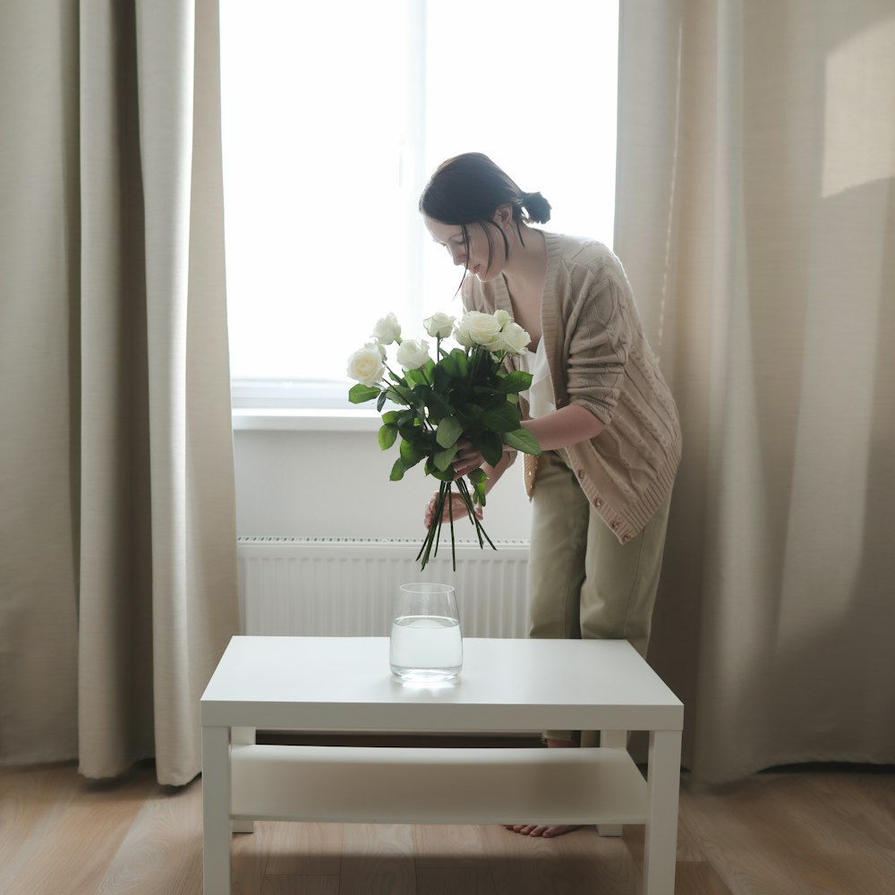 uma mulher em pé na frente de uma janela segurando um buquê de flores