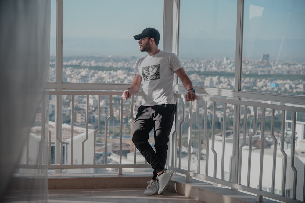 a man standing on top of a balcony next to a window