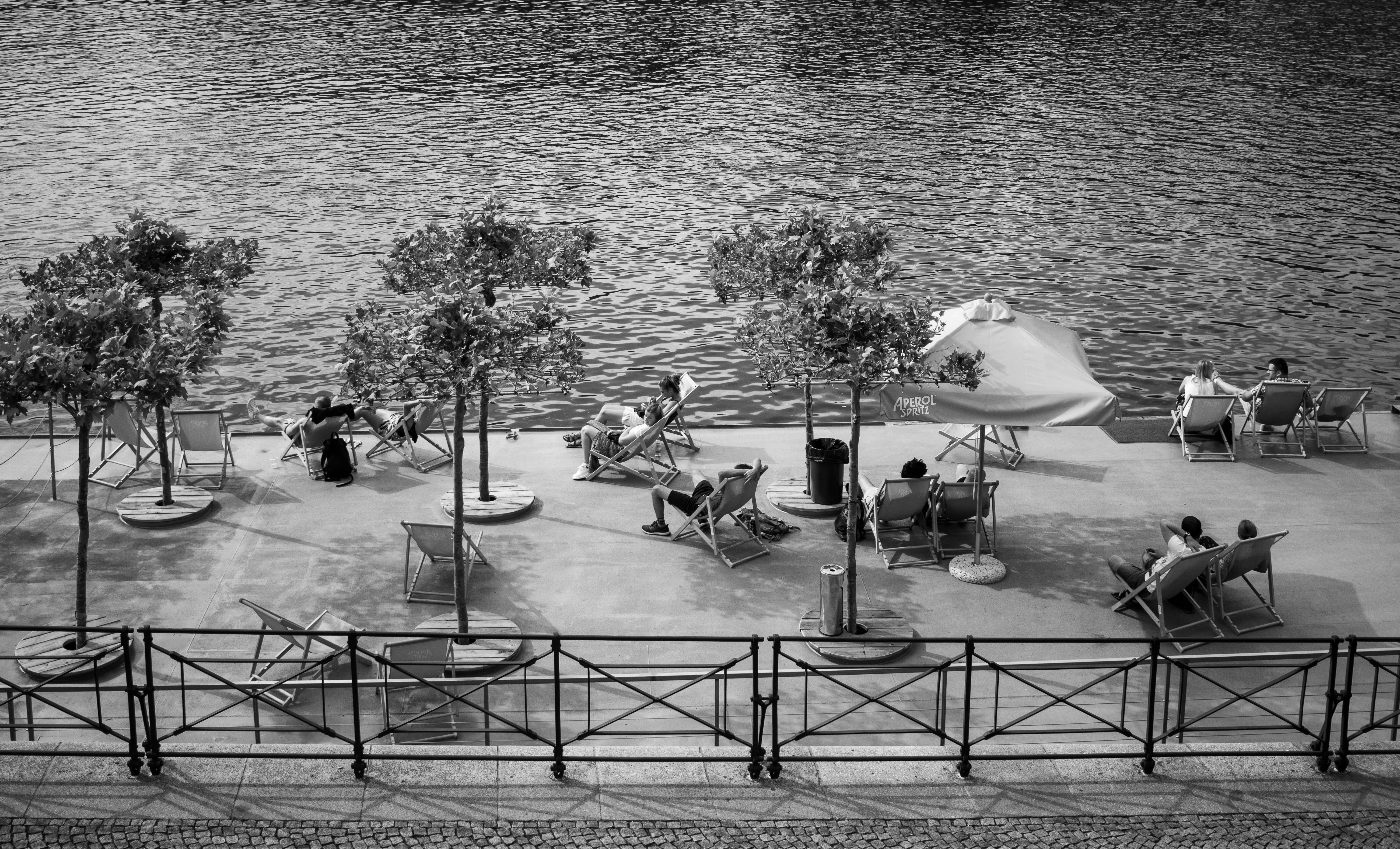 a black and white photo of people sitting on a pier