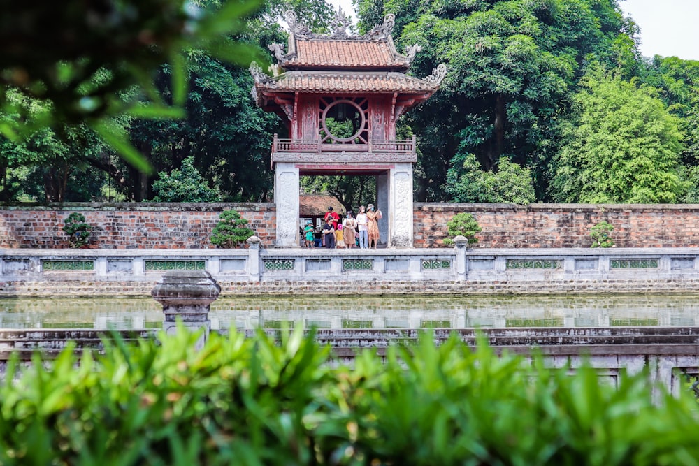a group of people standing around a pagoda in a park