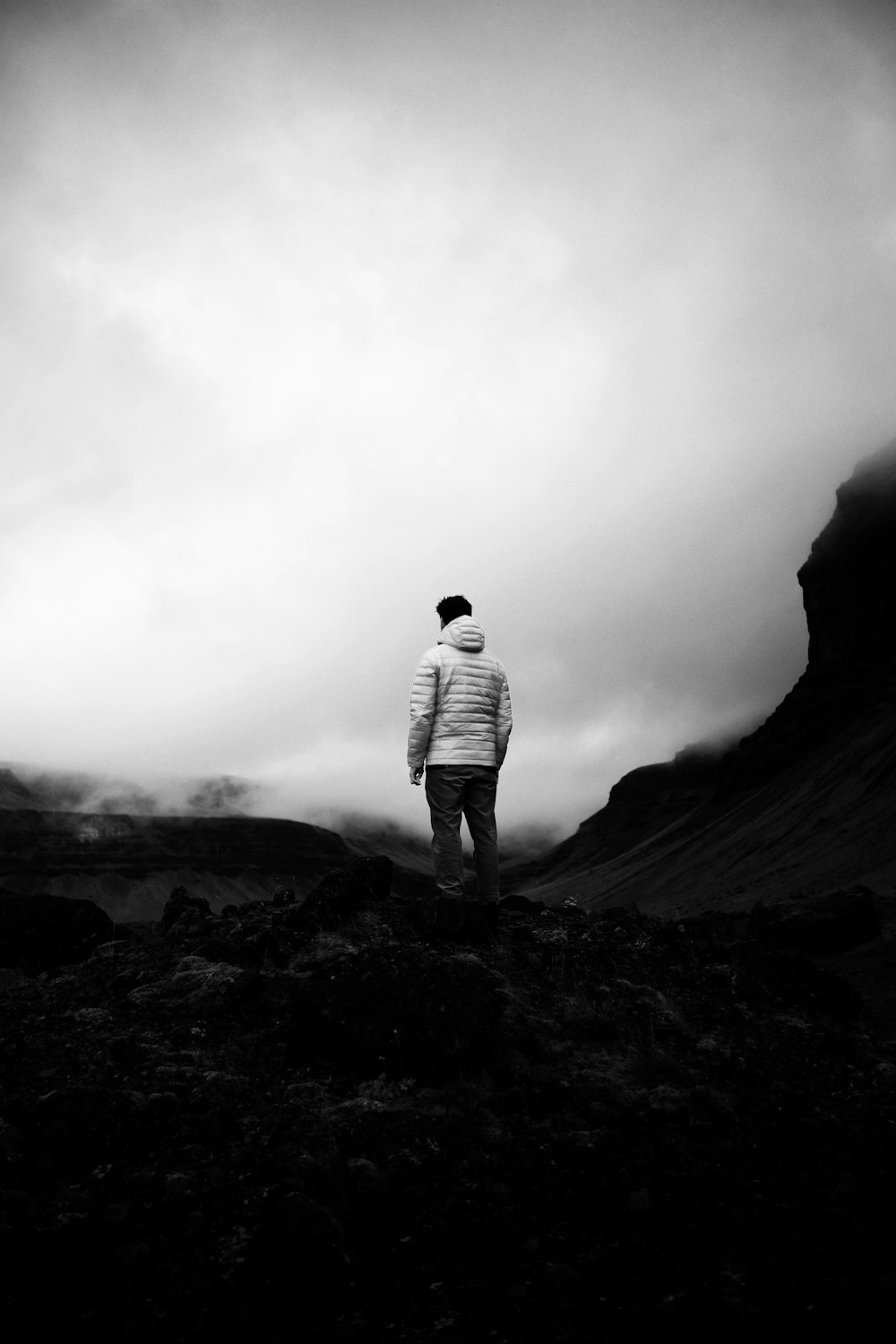 a man standing on top of a mountain under a cloudy sky