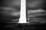 A historic lighthouse standing tall against a dramatic cloudy sky.