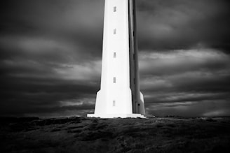 A lighthouse standing tall against a backdrop of stormy seas and darkening skies.