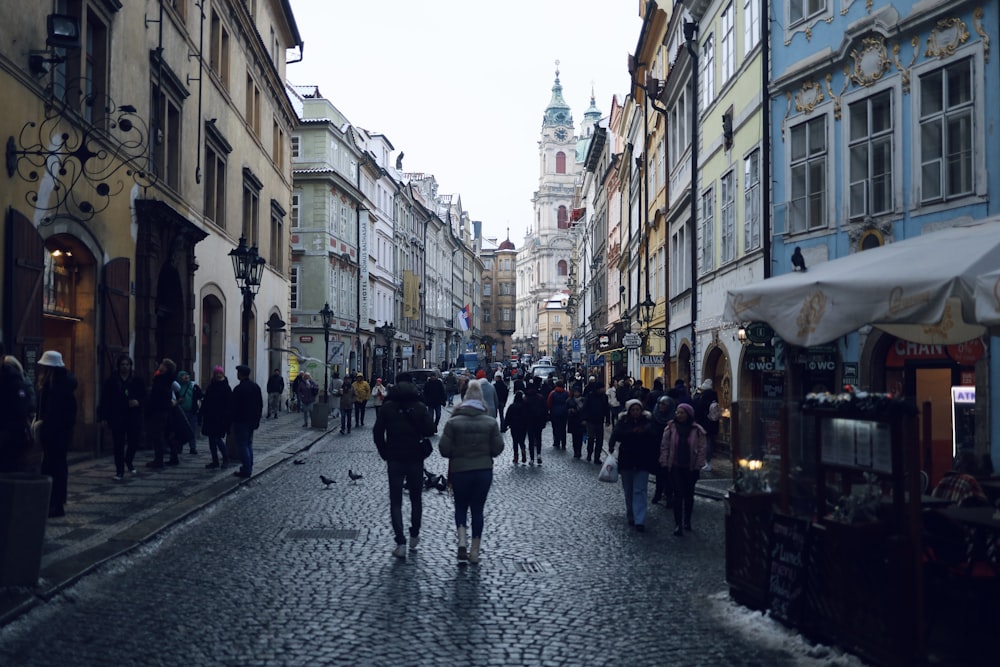 a group of people walking down a street next to tall buildings