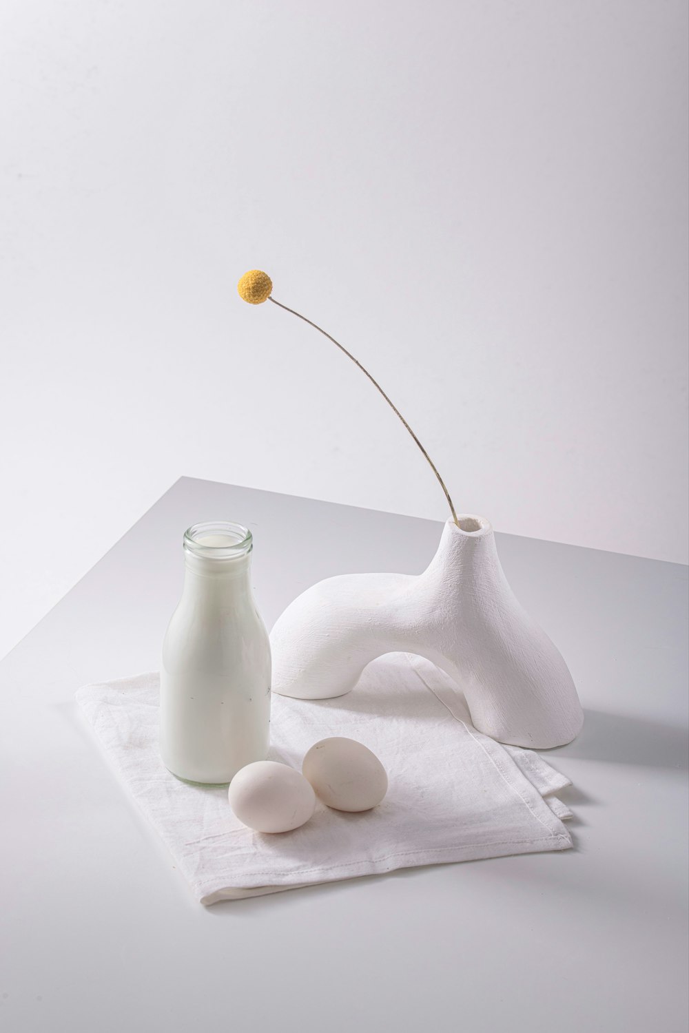 a vase with a flower and two eggs on a napkin