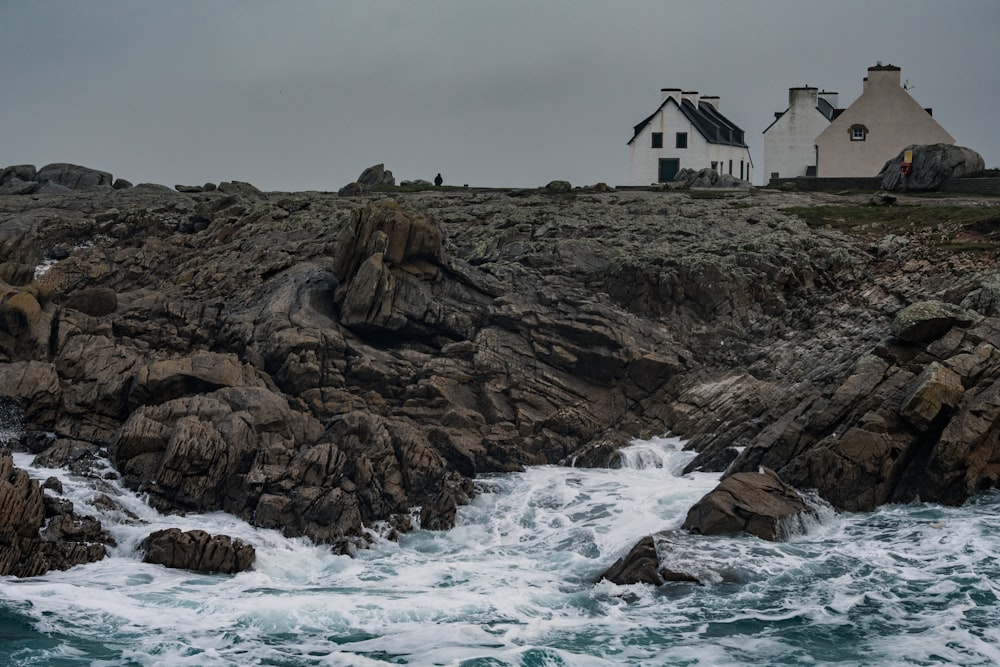 a house sitting on top of a rocky cliff next to the ocean
