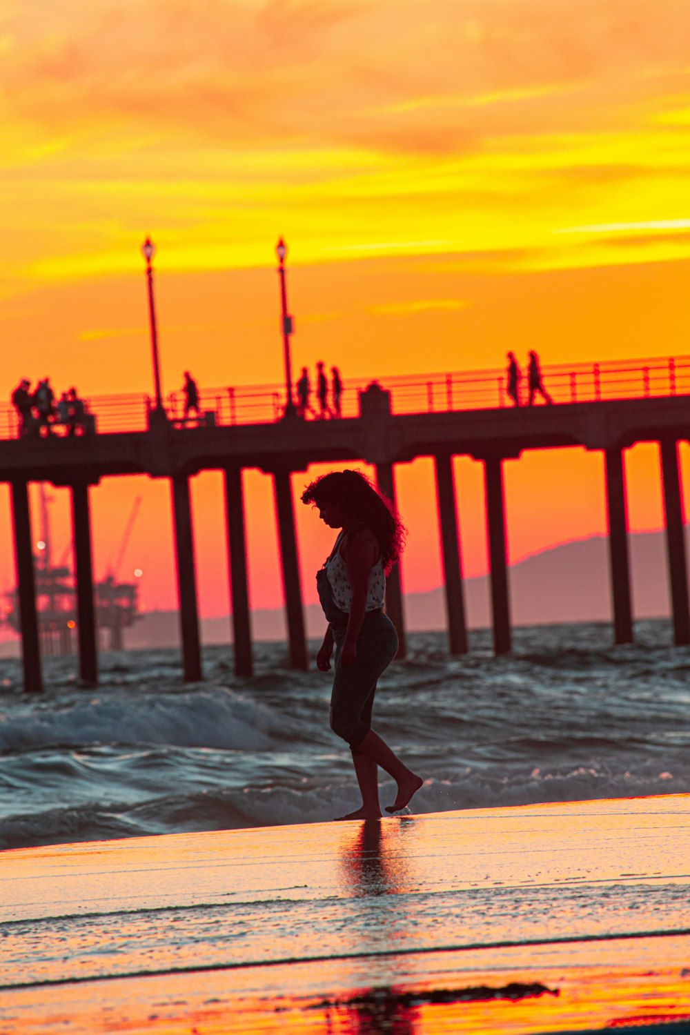 a woman walking on the beach at sunset