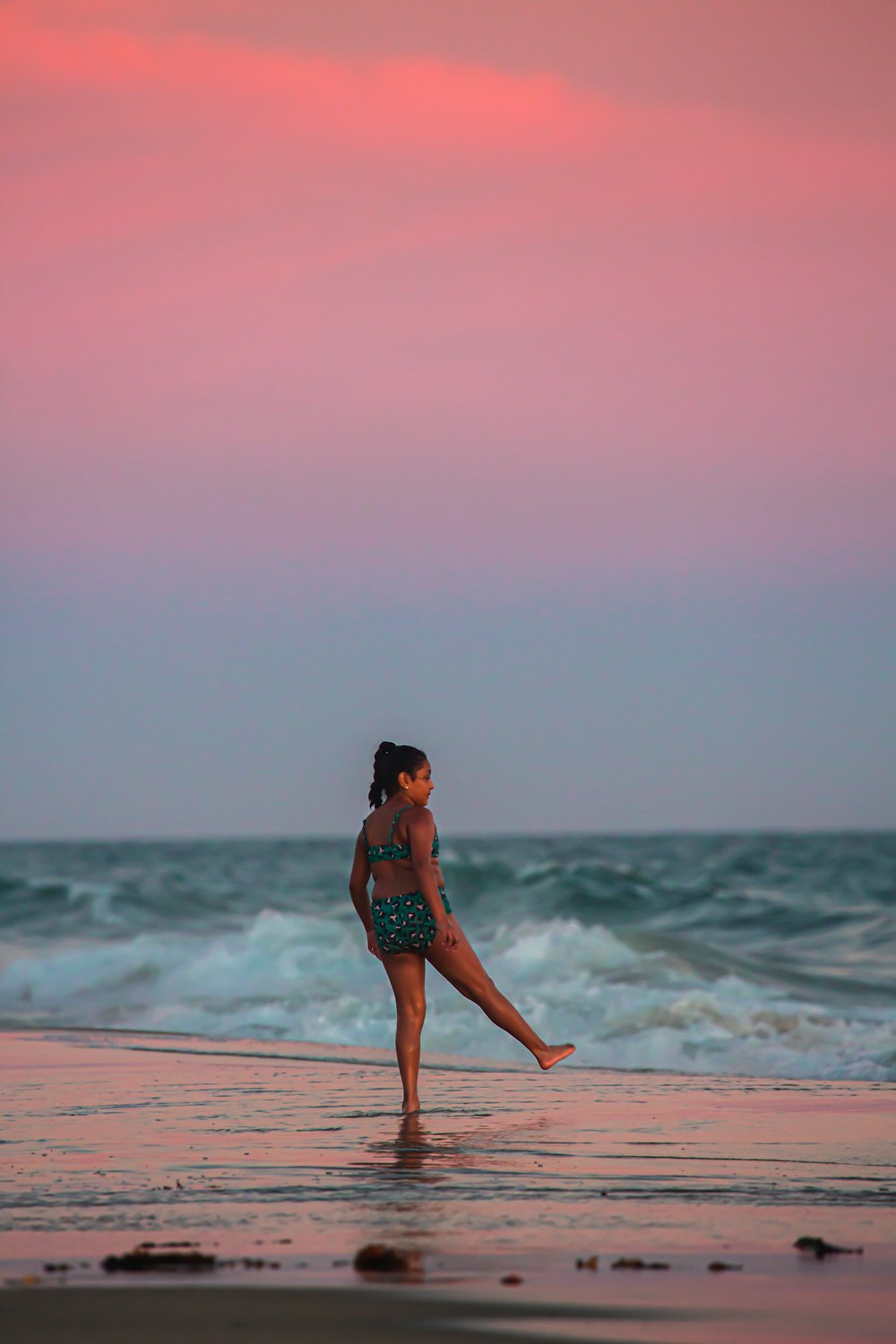 a woman standing on a beach next to the ocean