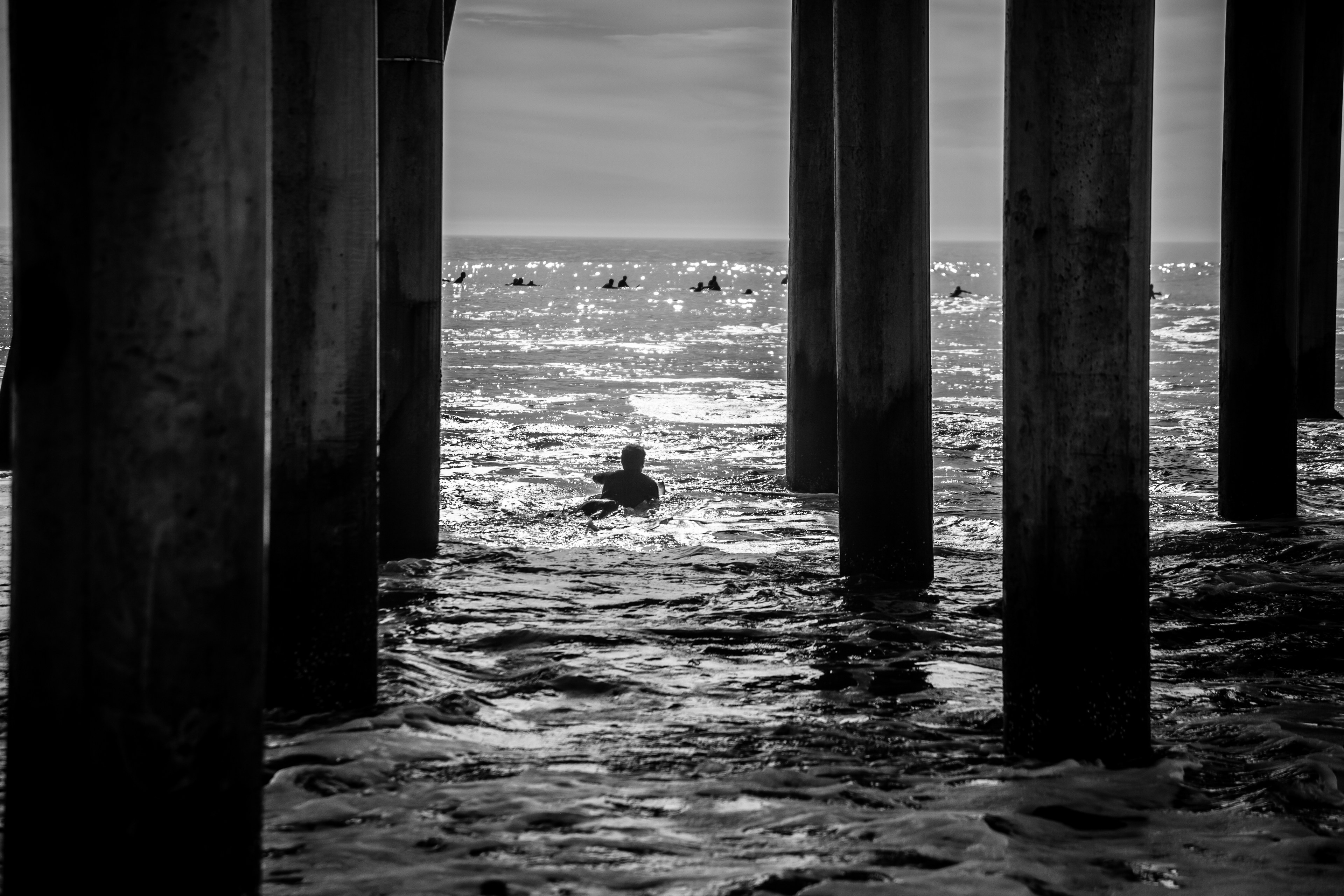 a person swimming under a pier in the ocean