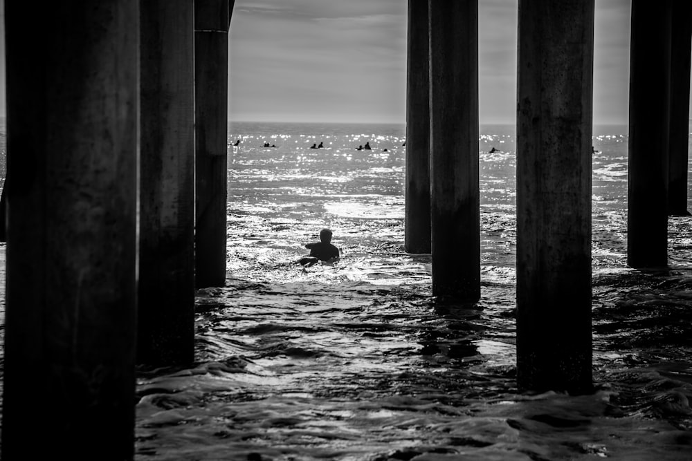 a person swimming under a pier in the ocean