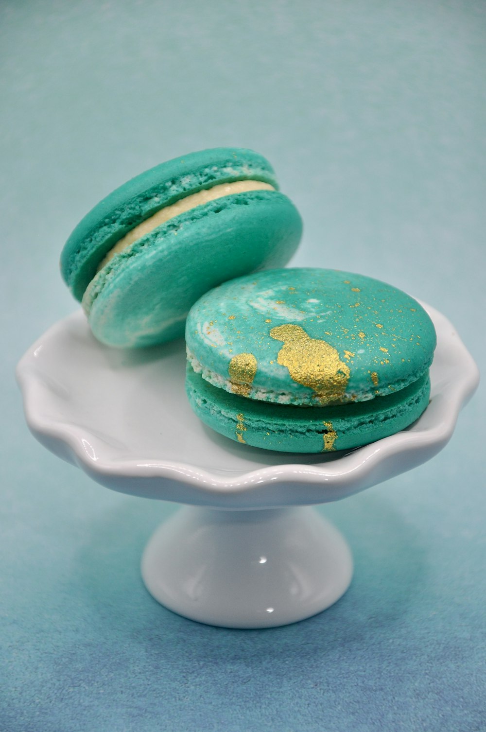 two green macaroons sitting on a white plate