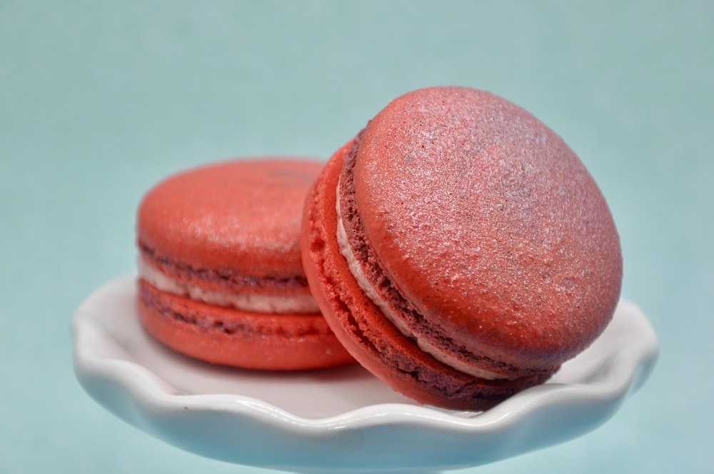 two red macaroons sitting on a white plate