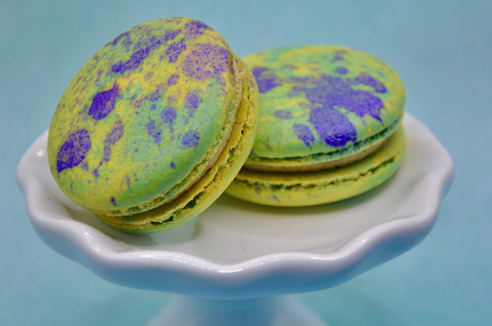 a white plate topped with green and purple macaroons