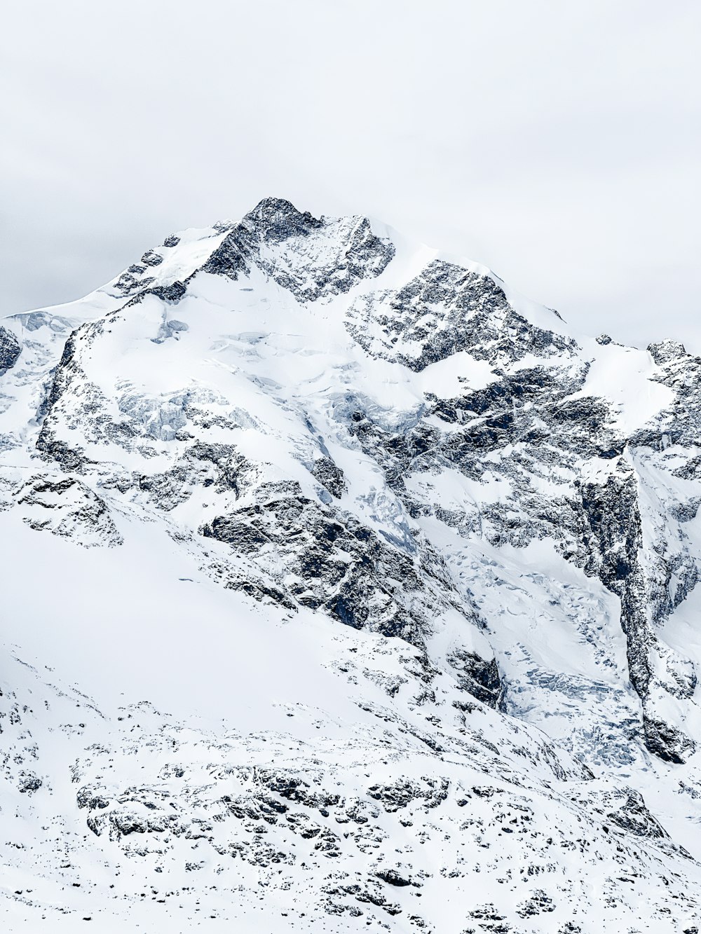 a mountain covered in snow with a sky background