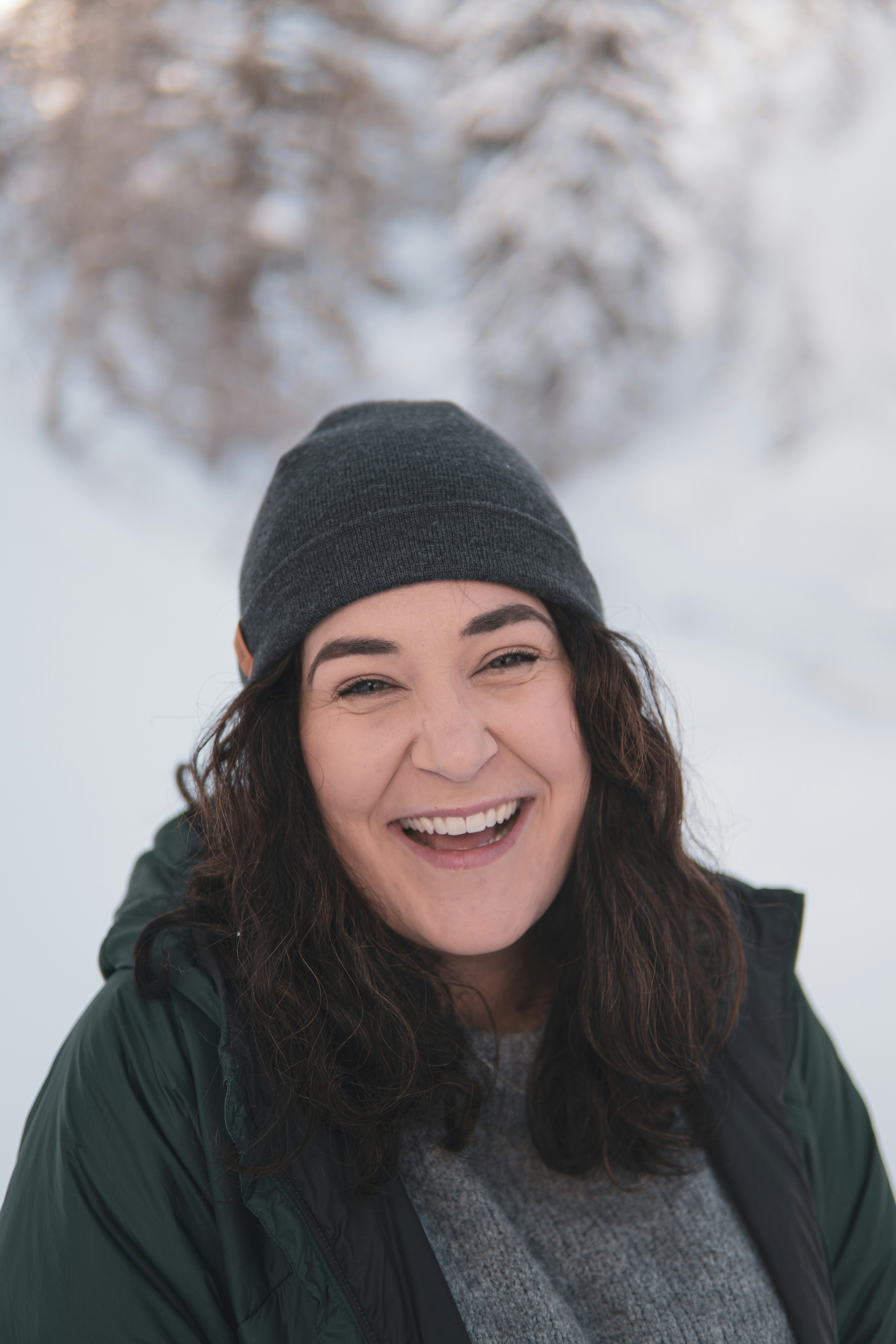 a smiling woman in a green jacket and a gray hat