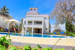 A modern aquatic facility with a large swimming pool and surrounding sports infrastructure under clear skies