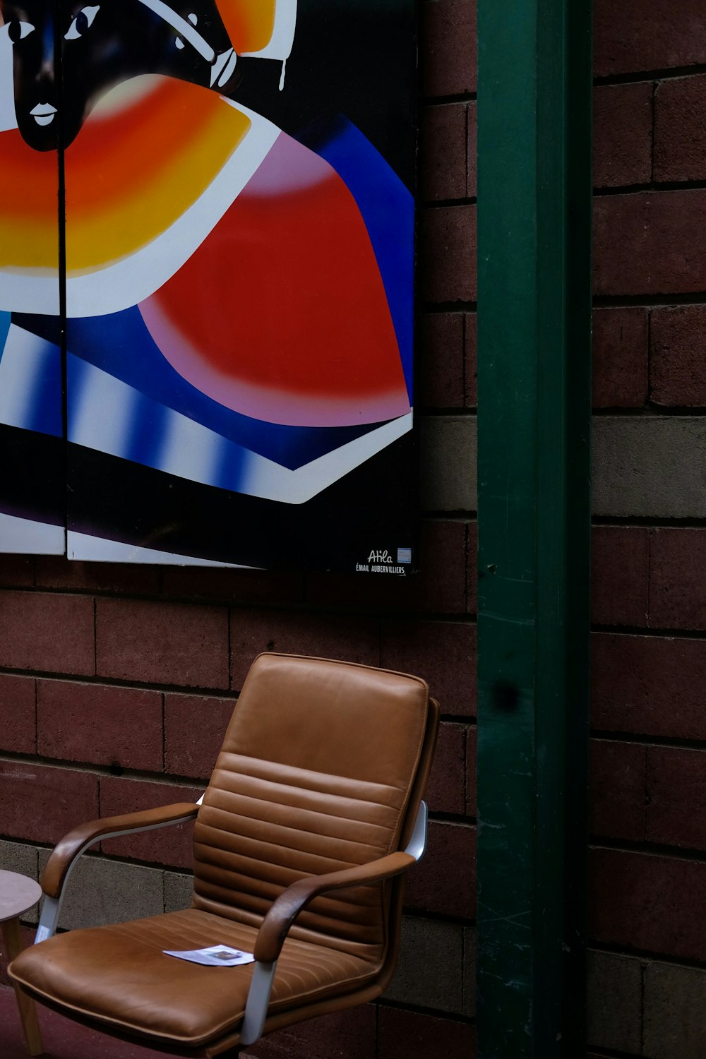 a brown leather chair sitting next to a brick wall