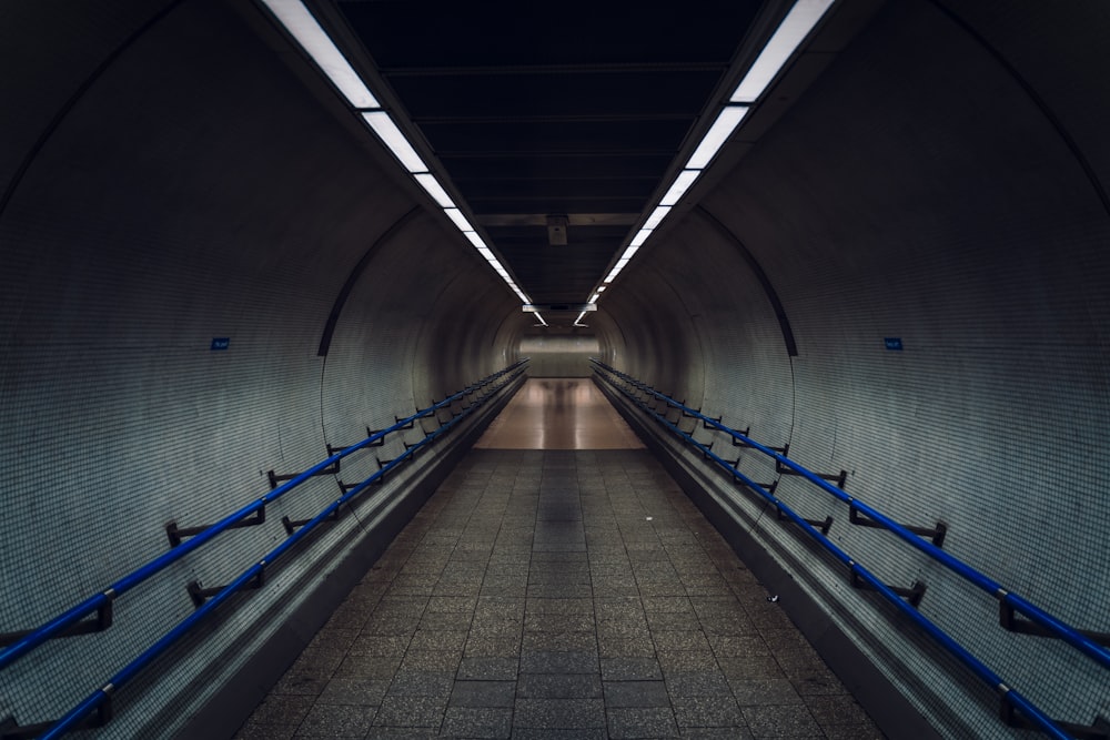 an empty subway tunnel with blue railings