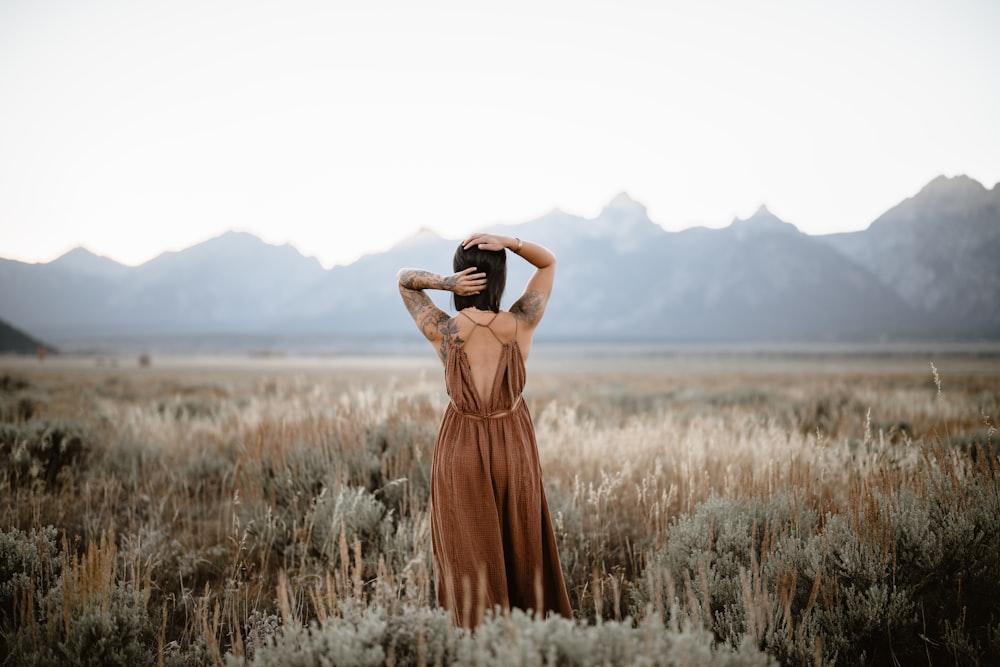 uma mulher de pé em um campo com as mãos na cabeça
