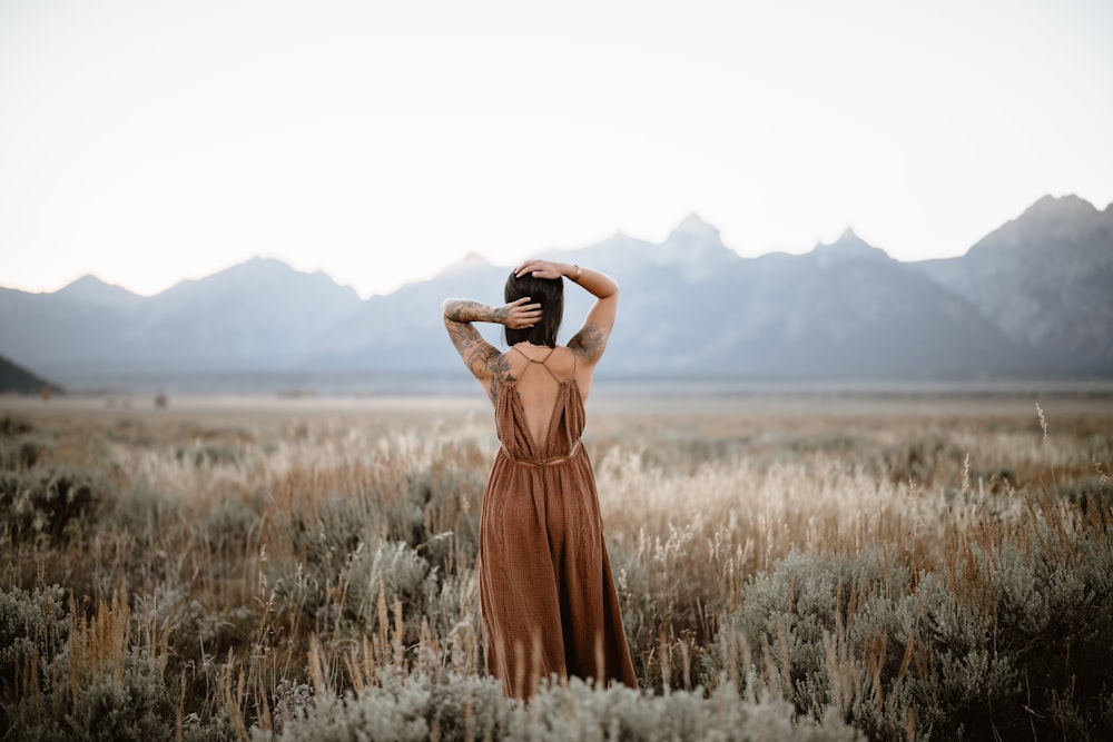 a woman standing in a field with her hands on her head