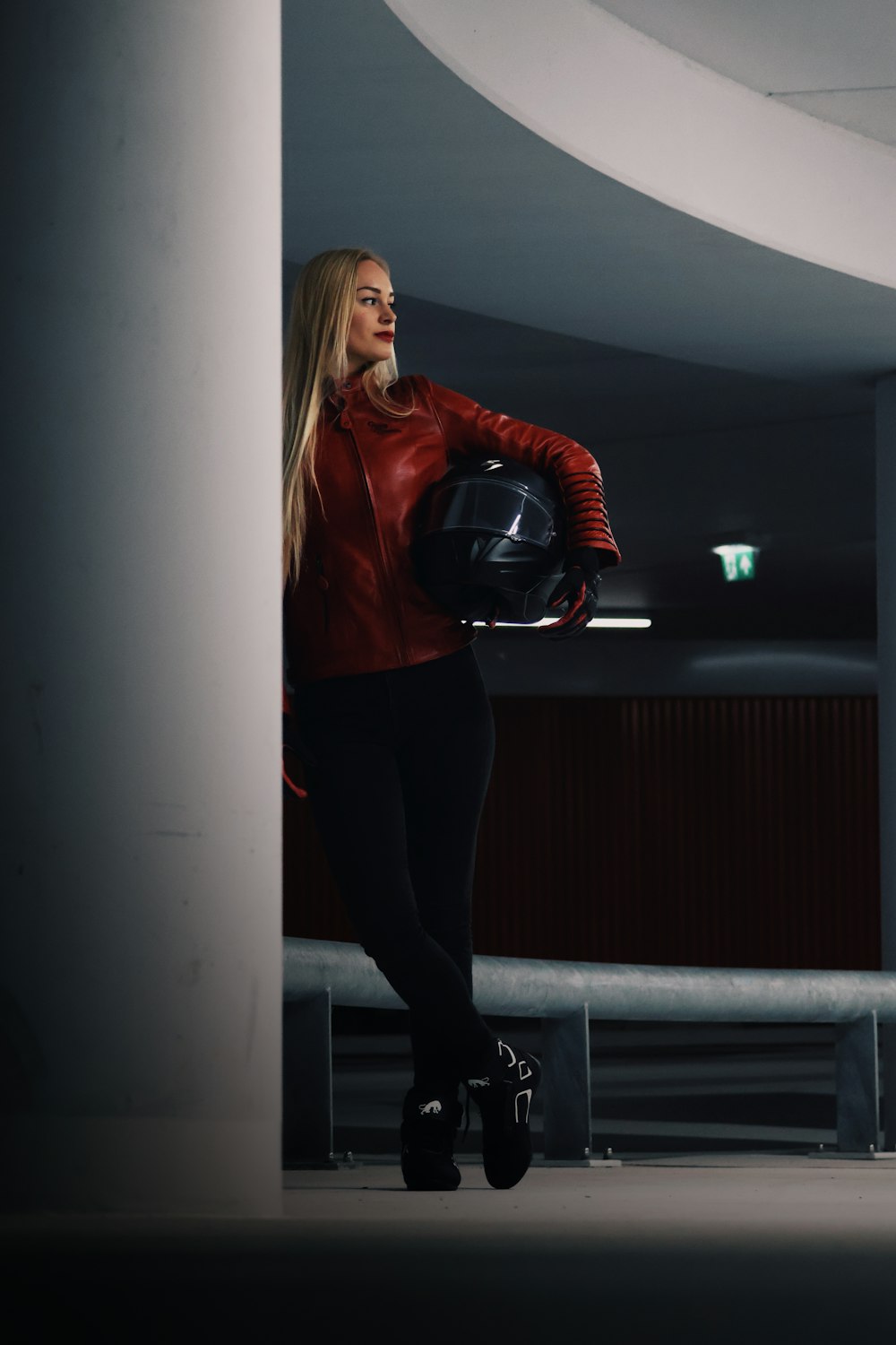 a woman in a red jacket is holding a helmet