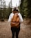 a woman wearing a brown backpack walking through a forest
