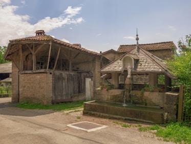 Old village fountain surrounded by blooming flowers and weathered stone walls