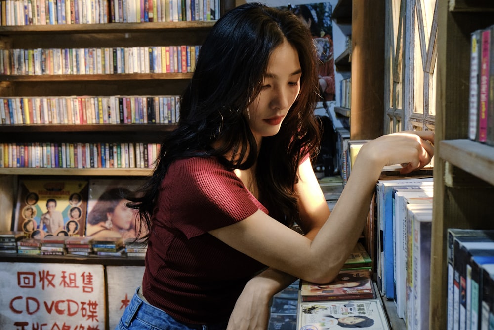 a woman looking through a book shelf in a bookstore