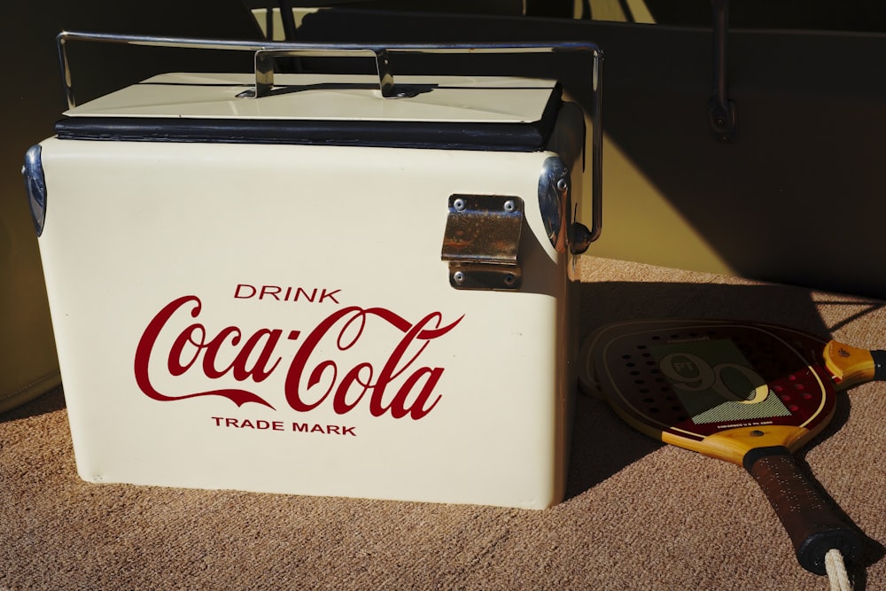 a cooler sitting on the ground next to a racquet