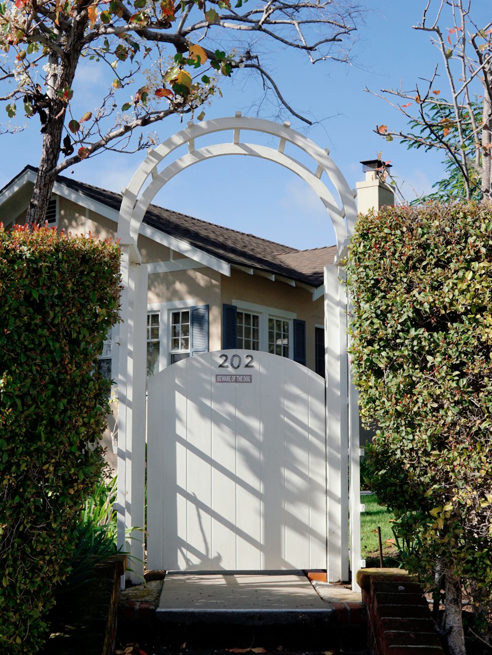 a white gate with a house in the background