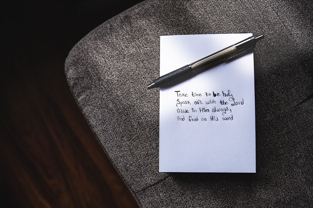 a note sitting on top of a chair next to a pen