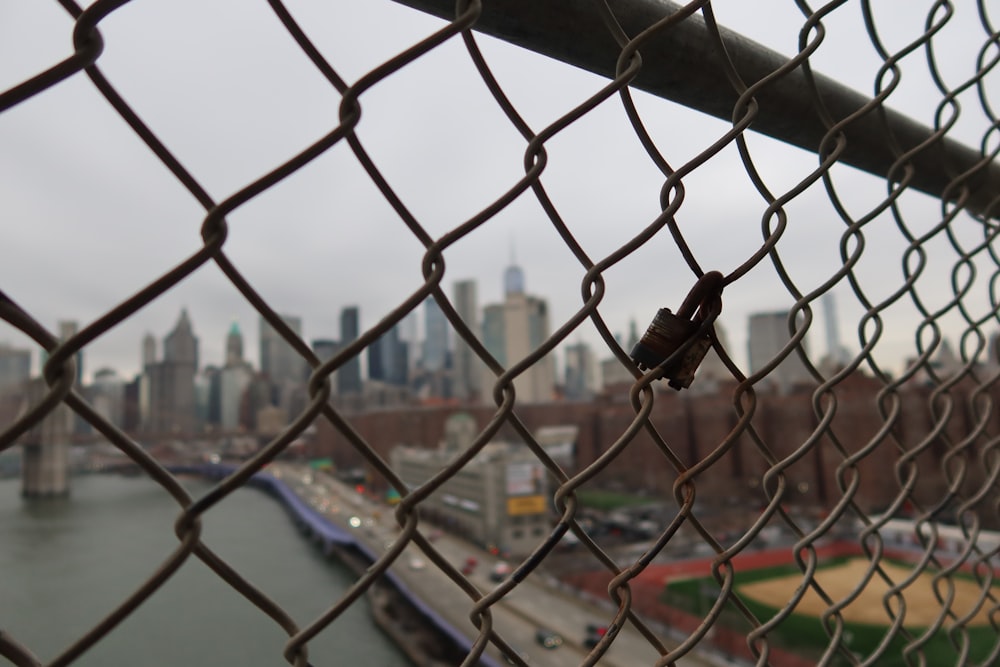 a chain link fence with a city in the background