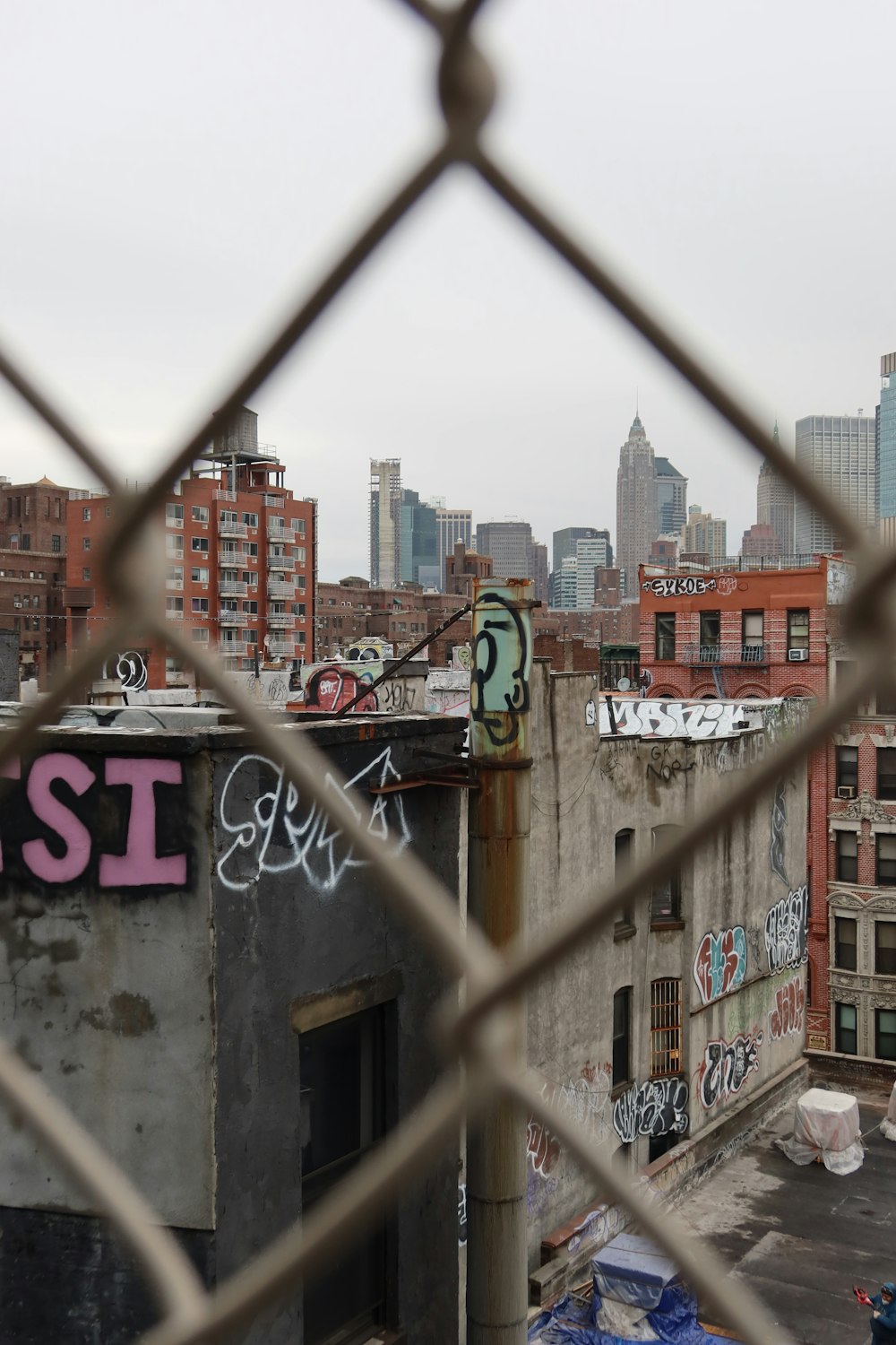 a view of a city through a chain link fence