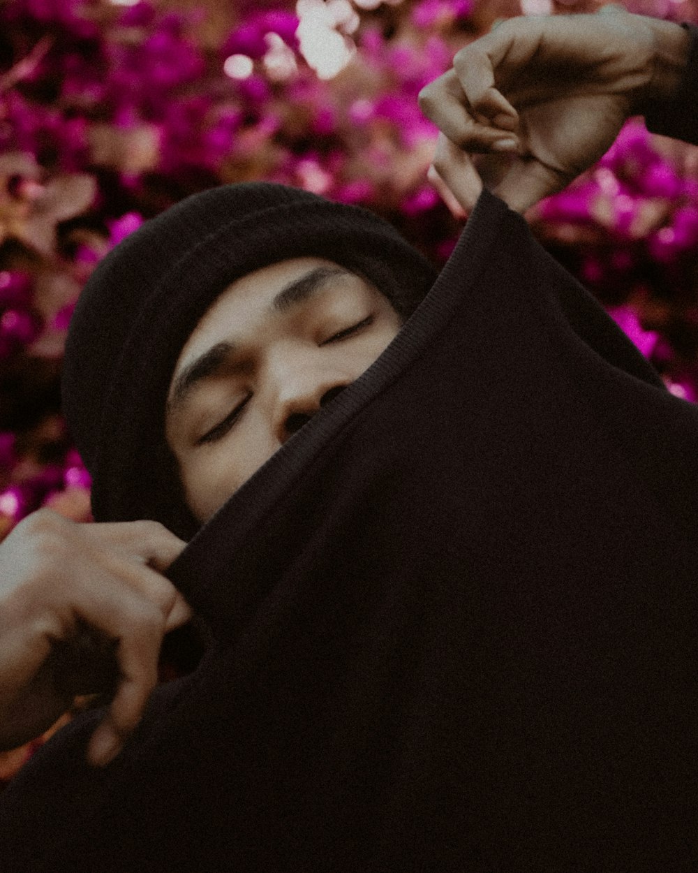 a man in a black hoodie is covering his face