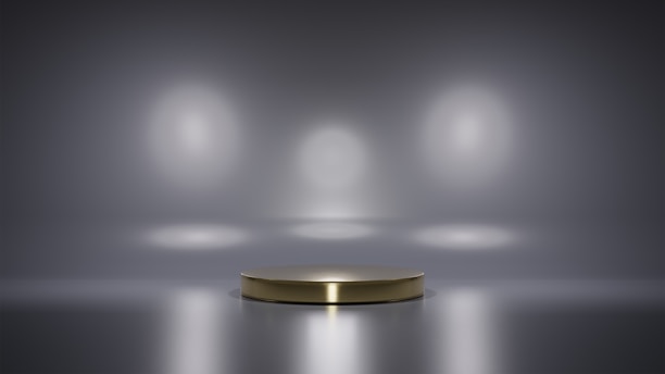 A metallic platform is centered in a minimalistic setting with a reflective surface. Soft, diffused lighting creates circular patterns on the background wall, enhancing the focus on the central stage. The ambiance is sleek and modern, with a hint of elegance.
